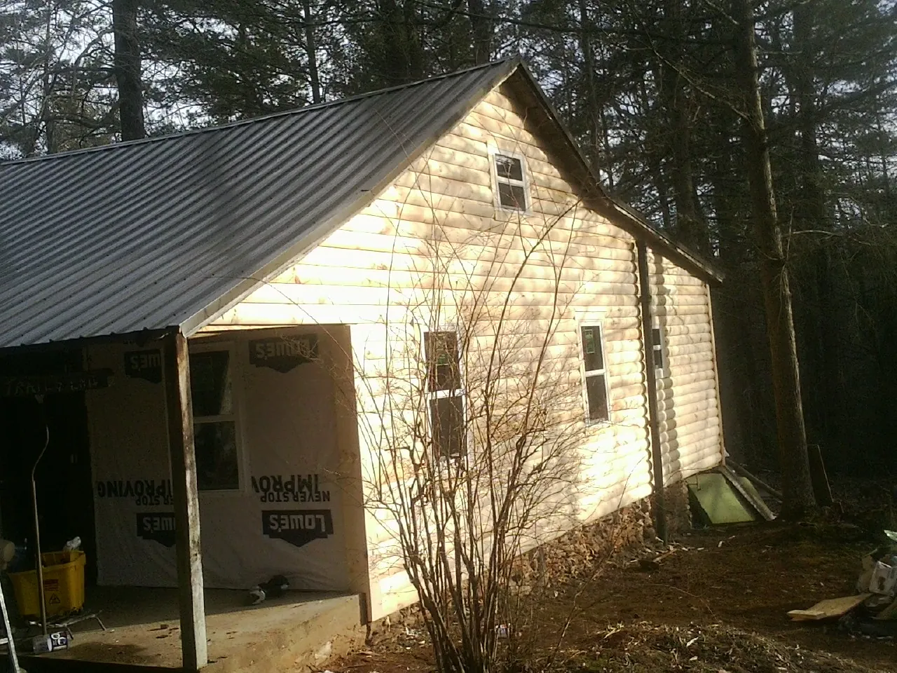 Log siding gable end under a dark metal roof edge in Yukon