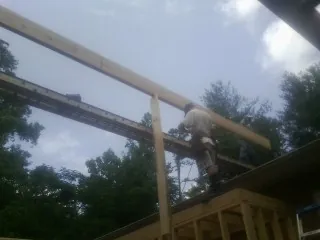 Carpenter setting a ridge beam over a new addition frame — Ice Dam Removal by Roofing Brothers in Yukon