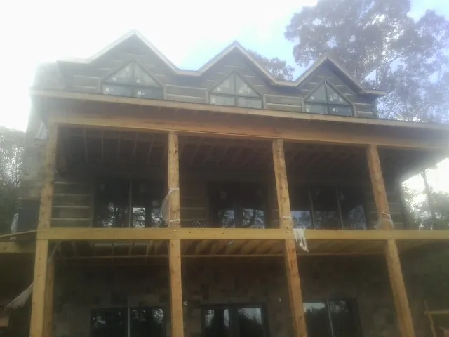 Dormers and porch framing on a large log home under construction — Roof Coating work by our crew in Yukon